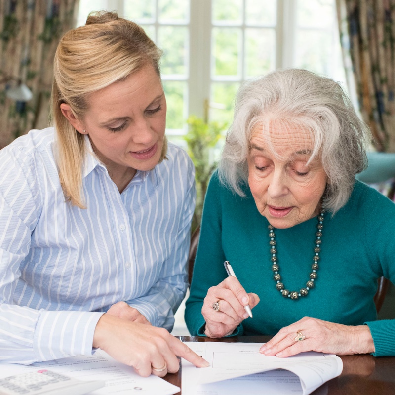 Young woman helping old woman with paperwork